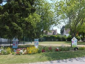 parc fleuri à l'entrée de l'école primaire avec décoration en bois peint.