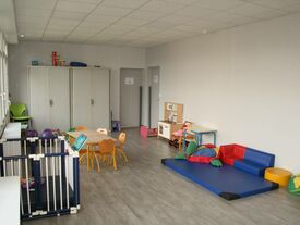 Salle d'accueil des familles avec des chaises, tables et jeux pour enfants de touts âges