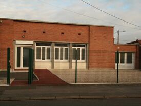 Façade avant en briques rouge et menuiseries extérieures en PVC Blanc.