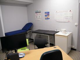 première salle avec table, chaises, ordinateur et lit médical de consultation