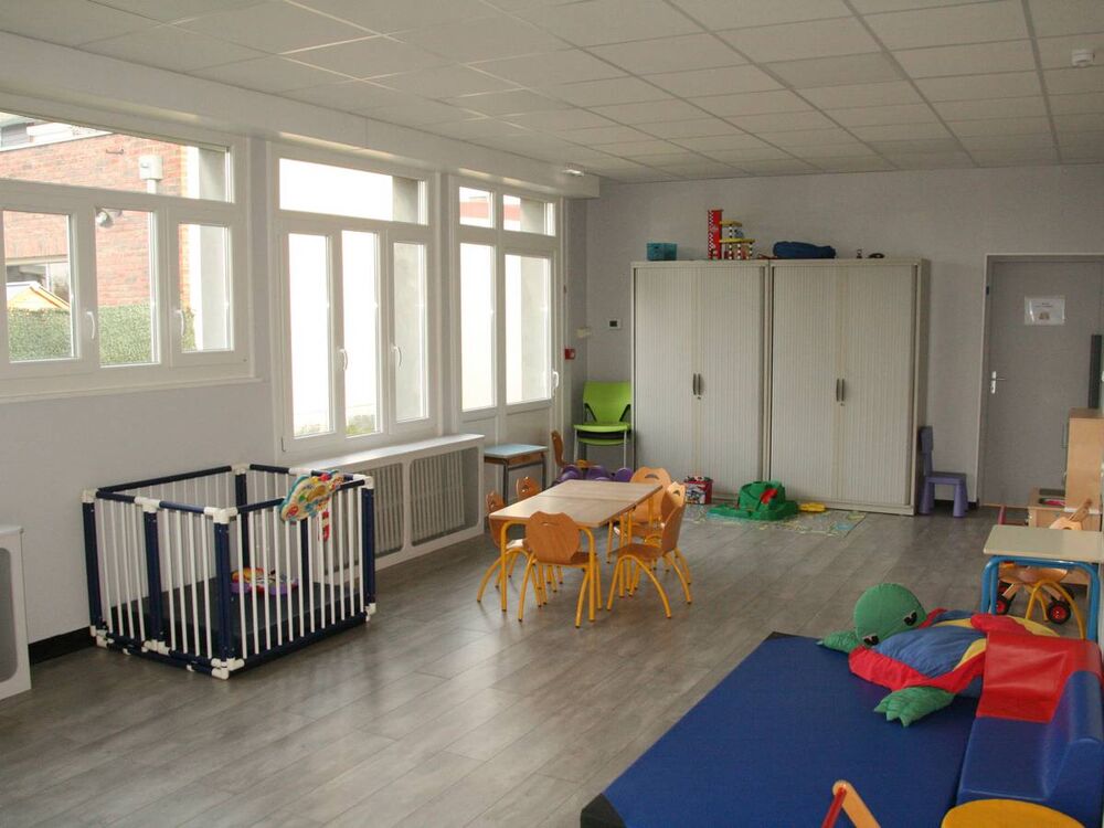 Salle d'accueil des familles avec des chaises, tables et jeux pour enfants de touts âges